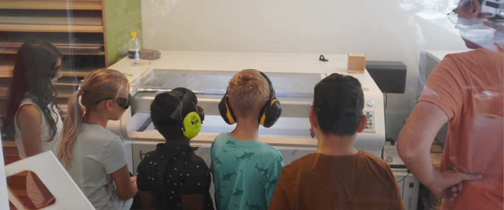 students and teacher using laser cutter